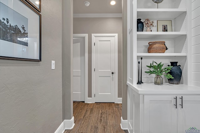 corridor with hardwood / wood-style flooring, crown molding, and built in features