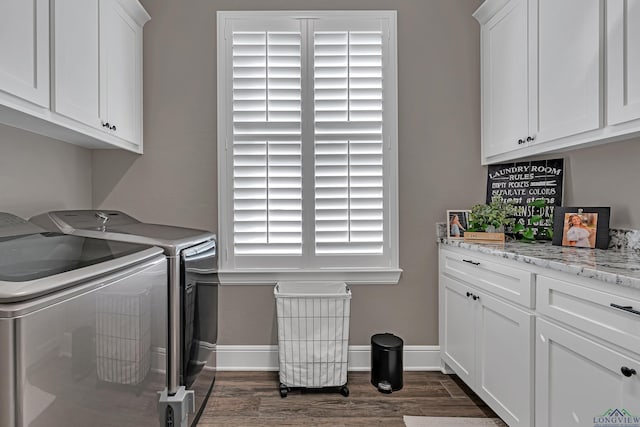 clothes washing area featuring dark hardwood / wood-style flooring, washing machine and dryer, and cabinets