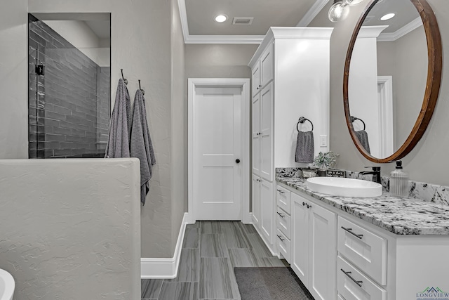 bathroom with crown molding, vanity, and a tile shower