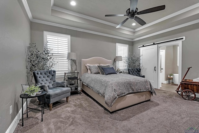 carpeted bedroom featuring a tray ceiling, crown molding, ceiling fan, and a barn door