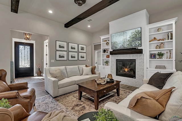 living room with a tile fireplace, hardwood / wood-style floors, and beam ceiling