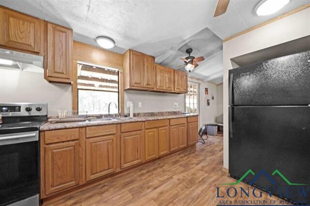 kitchen with stainless steel electric stove, black fridge, sink, light hardwood / wood-style flooring, and a textured ceiling