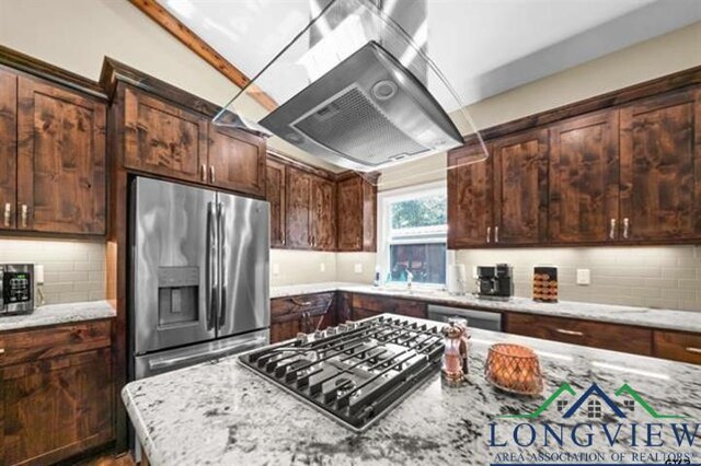 kitchen with light stone countertops, appliances with stainless steel finishes, tasteful backsplash, and island range hood