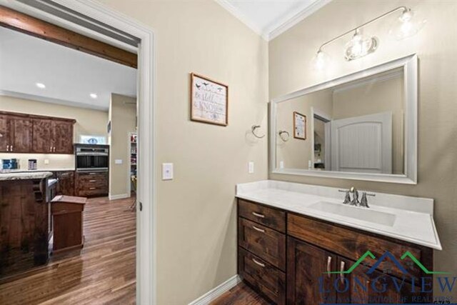 bathroom with wood-type flooring, vanity, and crown molding