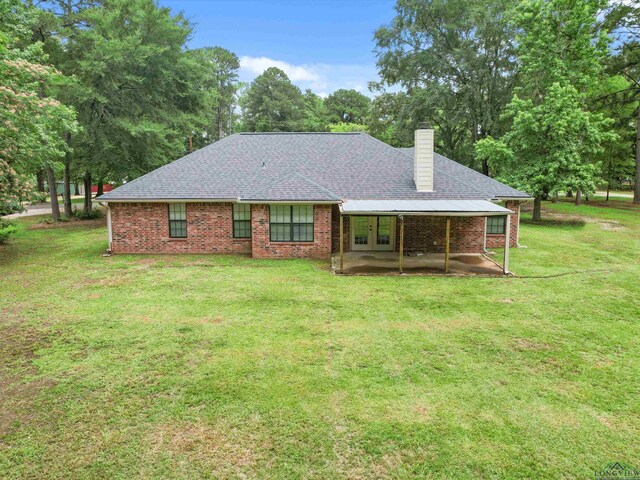 2015 W Lake Dr, Gladewater, TX 75647 - back of property with french doors, a chimney, a yard, a patio, and a shingled roof