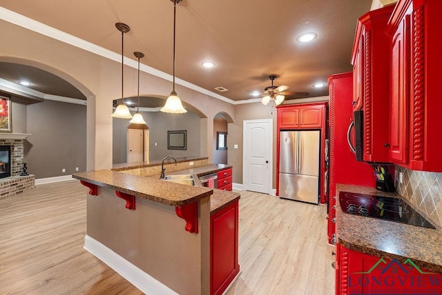 kitchen featuring ceiling fan, hanging light fixtures, stainless steel appliances, backsplash, and ornamental molding