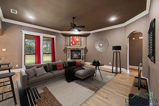 living room featuring a fireplace, ceiling fan, hardwood / wood-style floors, and ornamental molding