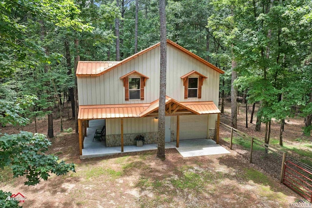 12493 S State Highway 87, Shelbyville, TX 75973 - view of front of home featuring board and batten siding, an attached garage, metal roof, driveway, and stone siding