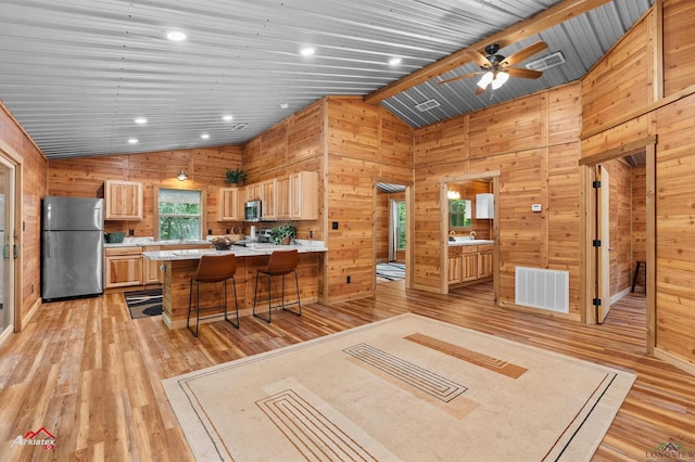 12493 S State Highway 87, Shelbyville, TX 75973 - kitchen featuring stainless steel appliances, light wood-style floors, light countertops, wood walls, and a peninsula