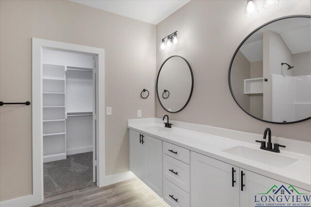 16226 Crossing Cir, Lindale, TX 75771 - full bath featuring double vanity, a walk in closet, a sink, and wood finished floors