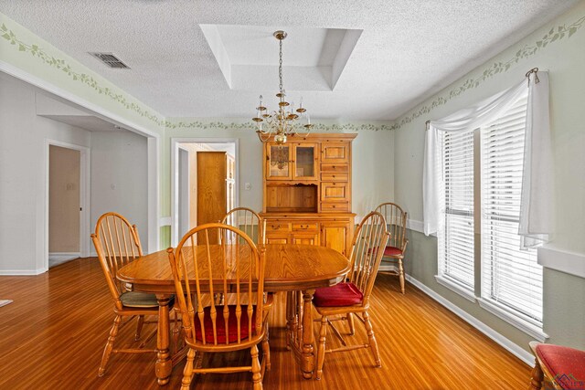 1208 Marigold Ln, Longview, TX 75604 - dining space with a textured ceiling, a chandelier, light wood-style flooring, and baseboards