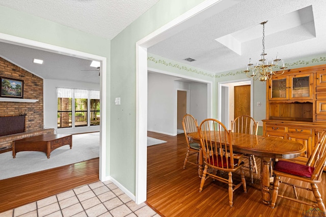 1208 Marigold Ln, Longview, TX 75604 - dining area with a textured ceiling, a fireplace, a chandelier, light wood finished floors, and vaulted ceiling