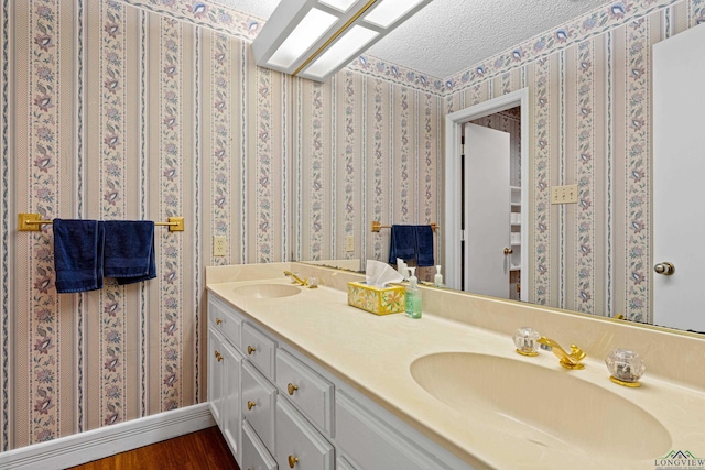 1208 Marigold Ln, Longview, TX 75604 - full bath with wood finished floors, double vanity, a textured ceiling, wallpapered walls, and baseboards