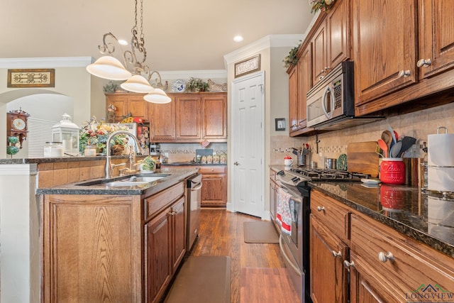 kitchen with stainless steel appliances, a kitchen island with sink, sink, pendant lighting, and dark hardwood / wood-style floors