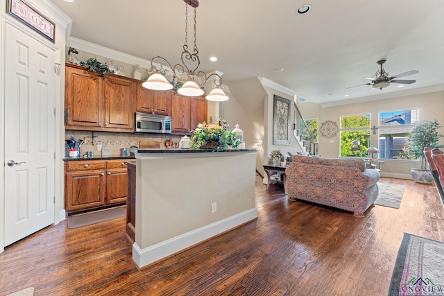 kitchen featuring backsplash, dark hardwood / wood-style flooring, decorative light fixtures, and ceiling fan with notable chandelier