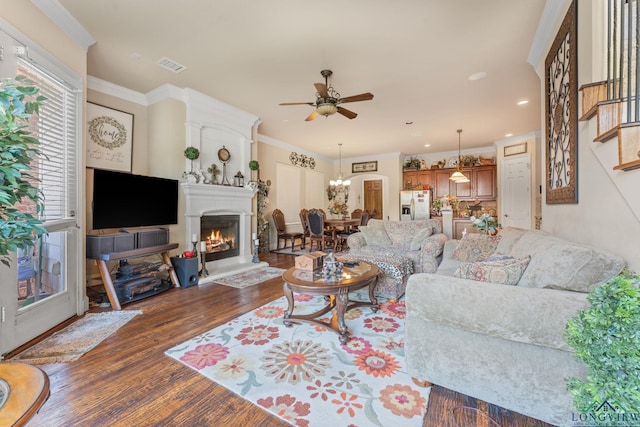 living room with crown molding, dark hardwood / wood-style floors, and ceiling fan with notable chandelier