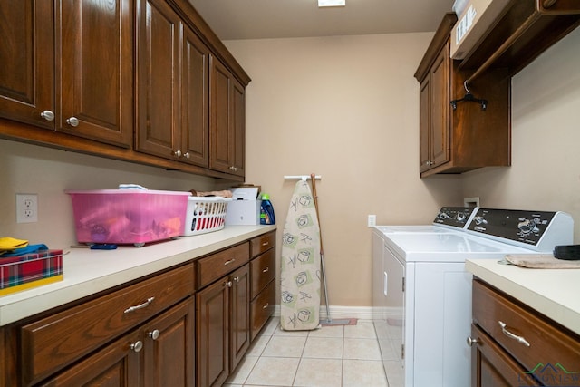 washroom with light tile patterned floors, cabinets, and washing machine and clothes dryer