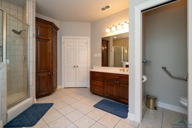 bathroom with tile patterned floors, toilet, a shower with door, and vanity