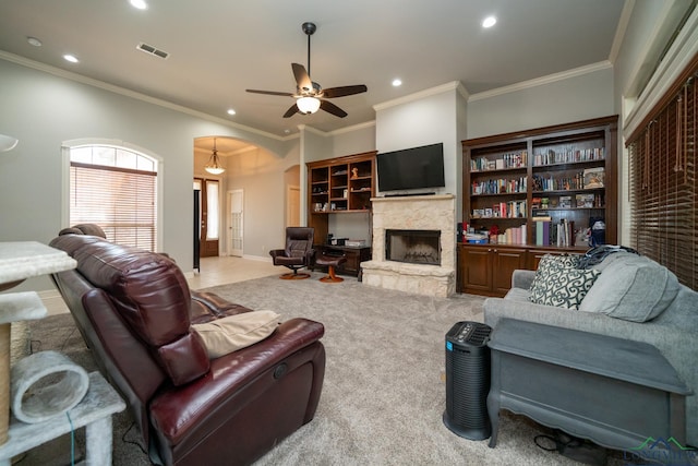 carpeted living room with ornamental molding, ceiling fan, and a fireplace