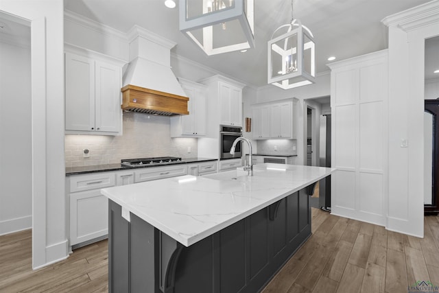 113 Saddle Brook Cir, Hallsville, TX 75650 - kitchen featuring custom range hood, stainless steel gas cooktop, light wood-style floors, white cabinets, and backsplash