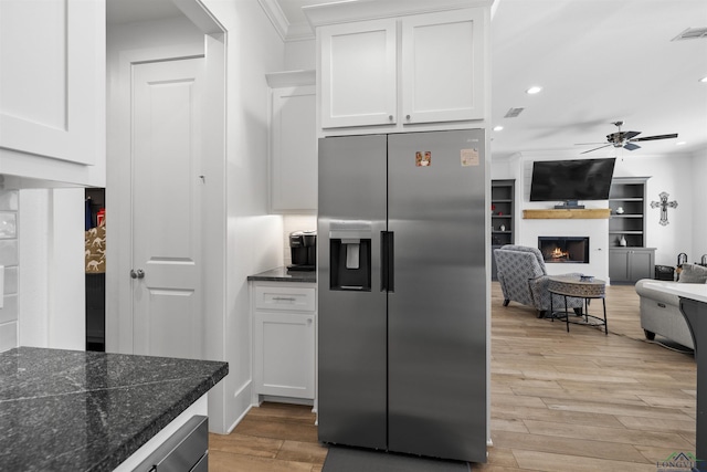 113 Saddle Brook Cir, Hallsville, TX 75650 - kitchen featuring stainless steel fridge, a ceiling fan, white cabinetry, light wood-style floors, and a lit fireplace
