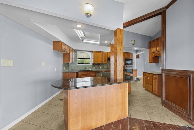 kitchen with dark stone counters, tasteful backsplash, a kitchen bar, and stainless steel appliances