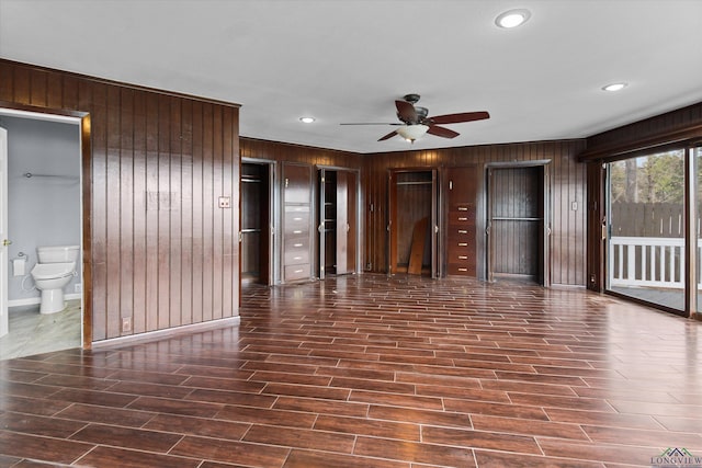 unfurnished room featuring ceiling fan and wood walls