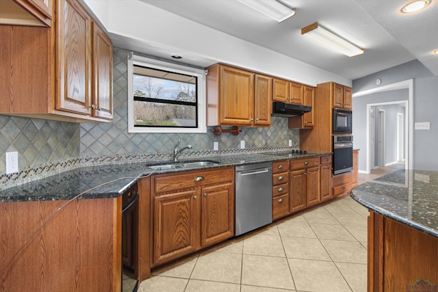 kitchen with dark stone countertops, sink, light tile patterned floors, and stainless steel appliances