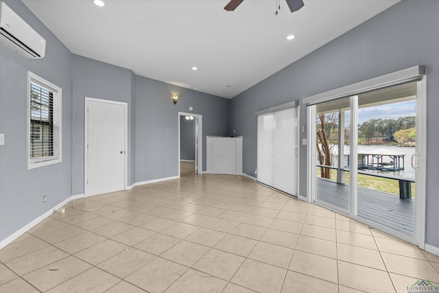 tiled spare room featuring ceiling fan, a wealth of natural light, a water view, and a wall unit AC