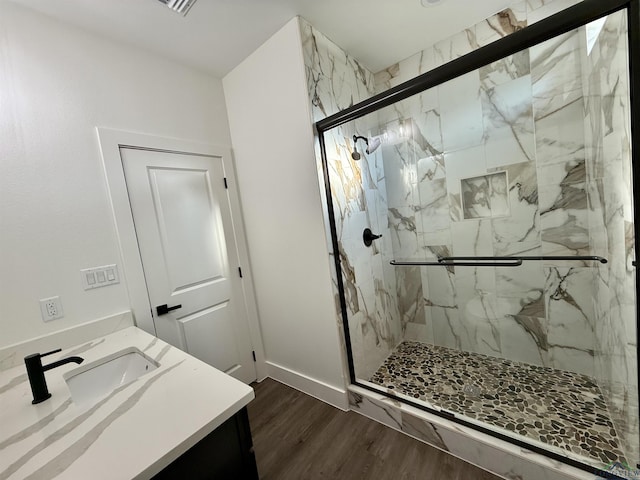 208 W Houston St, Daingerfield, TX 75638 - bathroom with wood finished floors, a marble finish shower, vanity, and baseboards