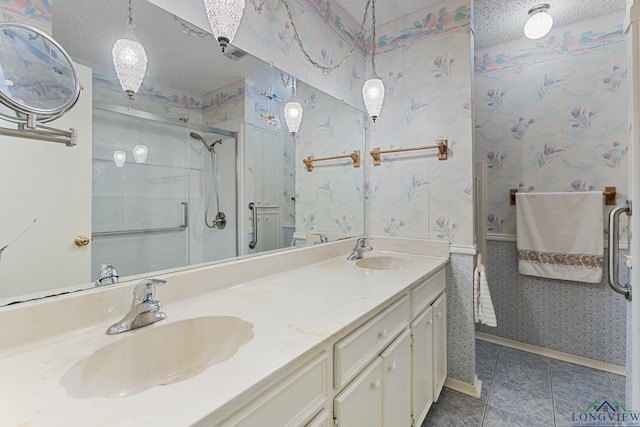 bathroom with tile patterned floors, vanity, a shower with door, and a textured ceiling