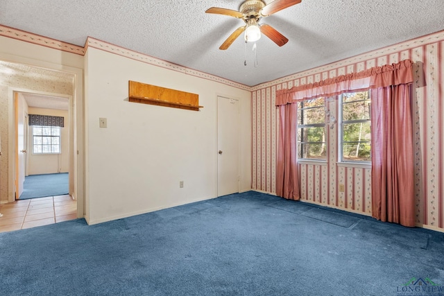 empty room featuring a textured ceiling, carpet floors, and ceiling fan