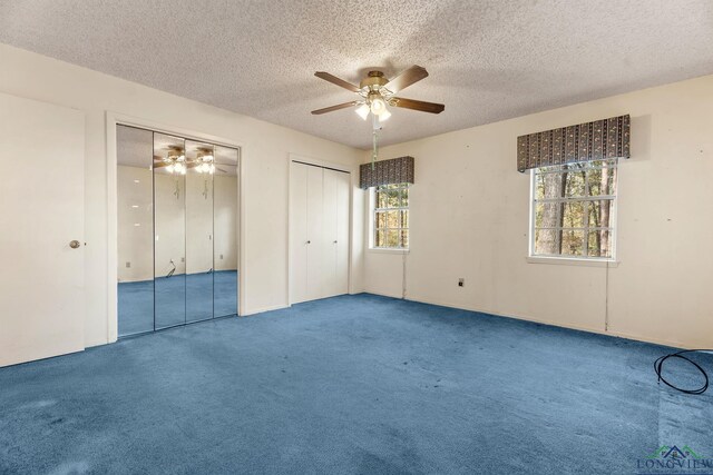 unfurnished bedroom featuring carpet flooring, a textured ceiling, ceiling fan, and multiple closets