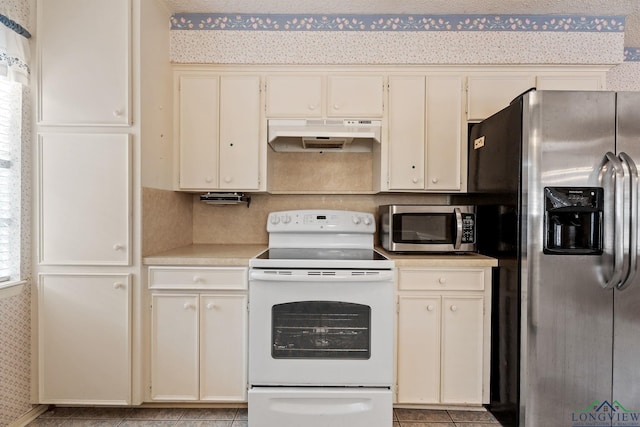 kitchen with cream cabinetry, appliances with stainless steel finishes, and light tile patterned flooring