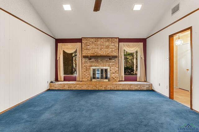 unfurnished living room with carpet flooring, wood walls, lofted ceiling, and a brick fireplace