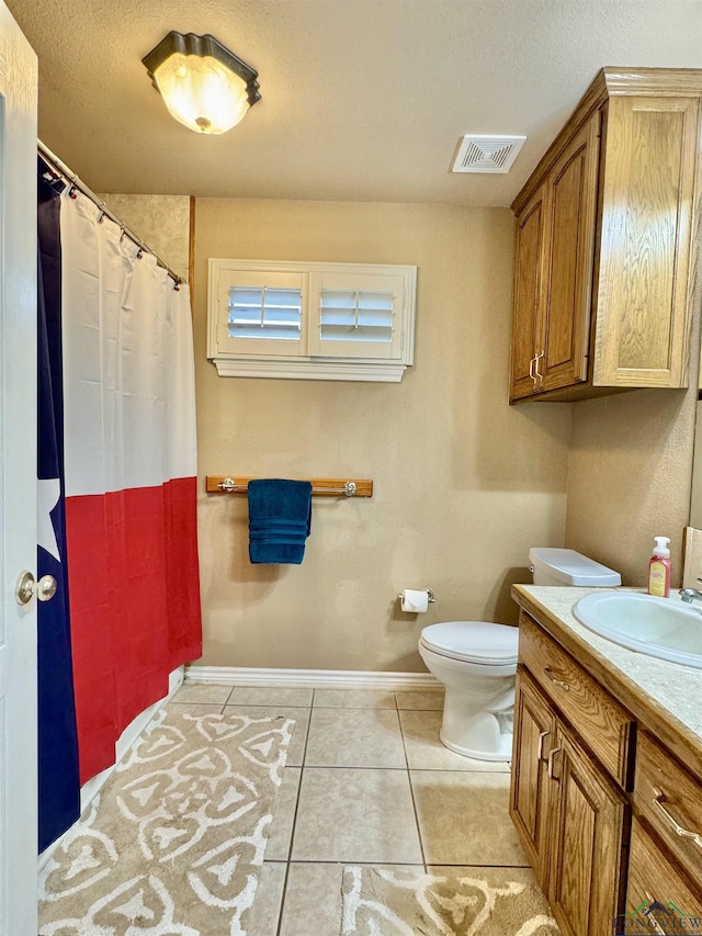 bathroom with tile patterned flooring, vanity, a textured ceiling, and toilet