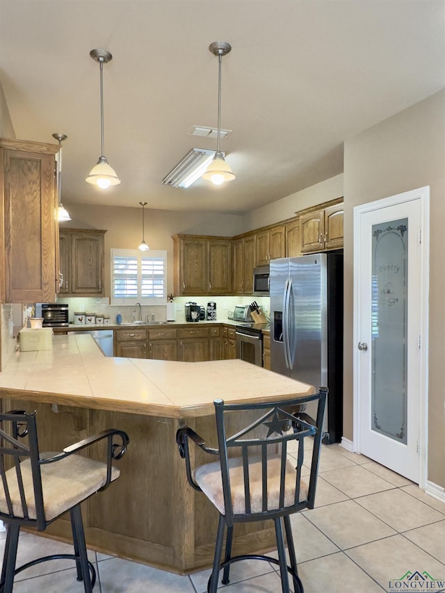 kitchen featuring kitchen peninsula, pendant lighting, a breakfast bar, and stainless steel appliances