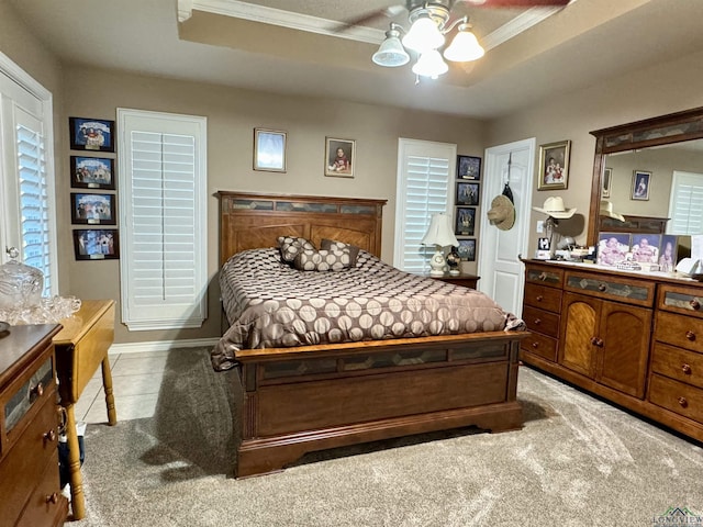 bedroom featuring a raised ceiling, ceiling fan, and light carpet