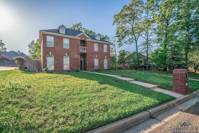 colonial home with a front yard, fence, and brick siding