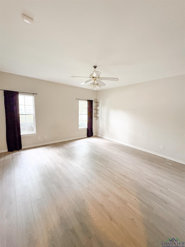 unfurnished room with a ceiling fan, light wood-style flooring, and baseboards