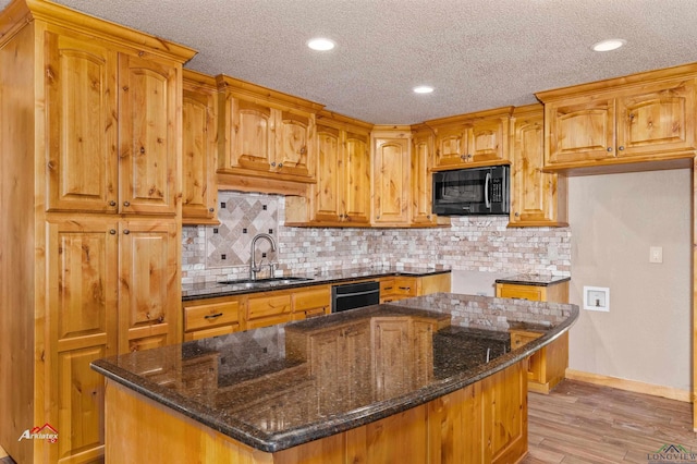 kitchen featuring sink, a center island, dark stone counters, and black appliances