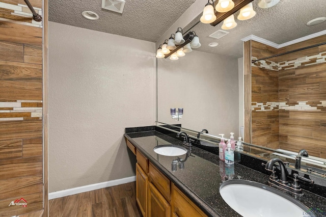 bathroom with vanity, a textured ceiling, hardwood / wood-style flooring, and crown molding