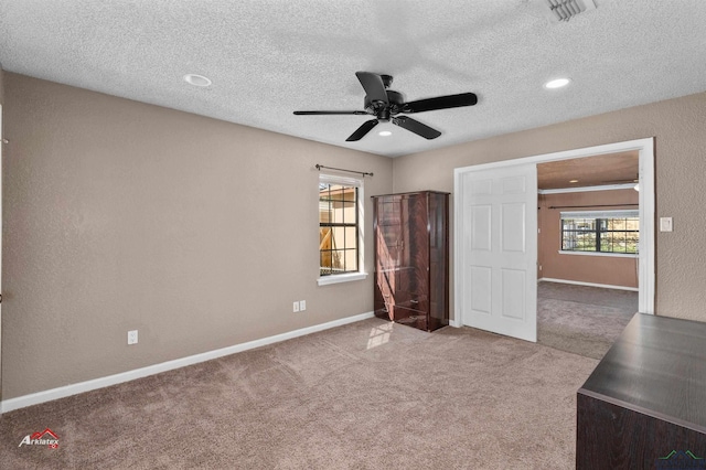 unfurnished bedroom with a textured ceiling, ceiling fan, and light carpet