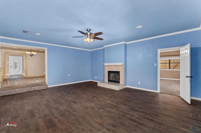 unfurnished living room with dark hardwood / wood-style flooring, ceiling fan with notable chandelier, a textured ceiling, crown molding, and a tiled fireplace