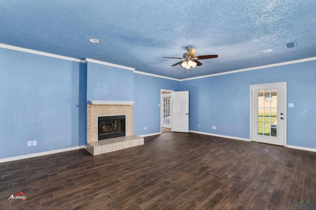 unfurnished living room featuring dark wood-type flooring, a tile fireplace, ceiling fan, ornamental molding, and a textured ceiling