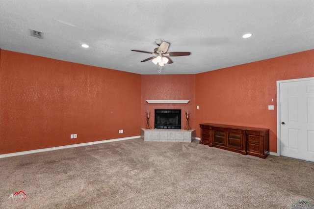 unfurnished living room featuring carpet flooring, a textured ceiling, a fireplace, and ceiling fan