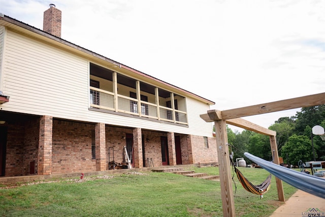 back of house with a lawn and a balcony