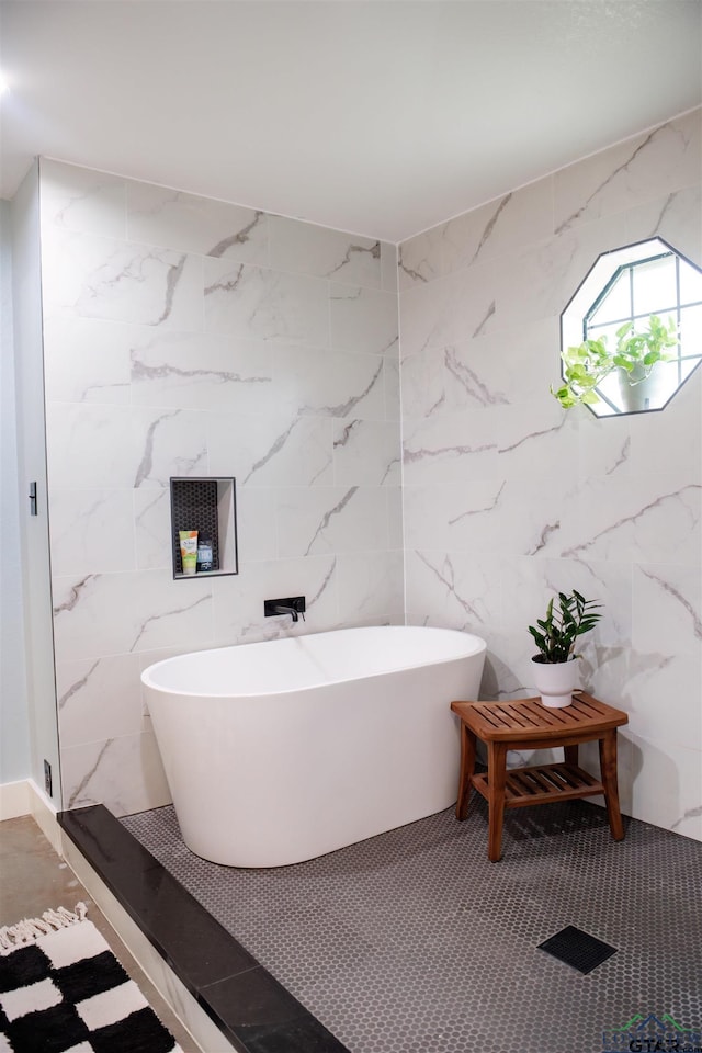 bathroom featuring a washtub and tile walls