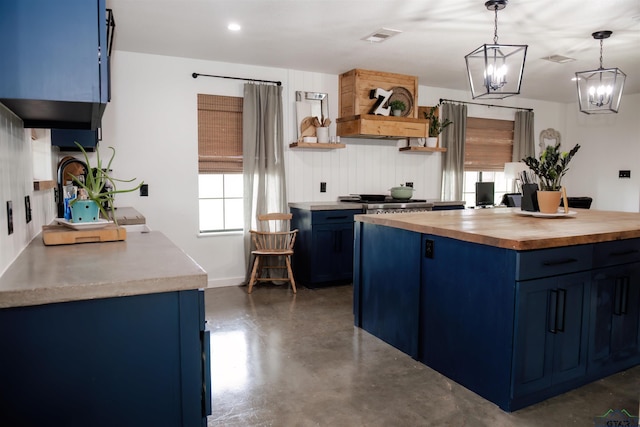 kitchen with a notable chandelier, butcher block countertops, blue cabinets, pendant lighting, and stainless steel gas stovetop