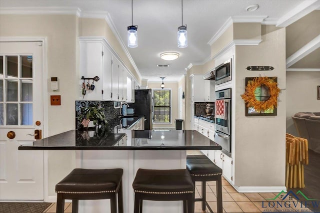 918 S Evenside St, Henderson, TX 75654 - kitchen with stainless steel appliances, a warming drawer, ornamental molding, tasteful backsplash, and a peninsula